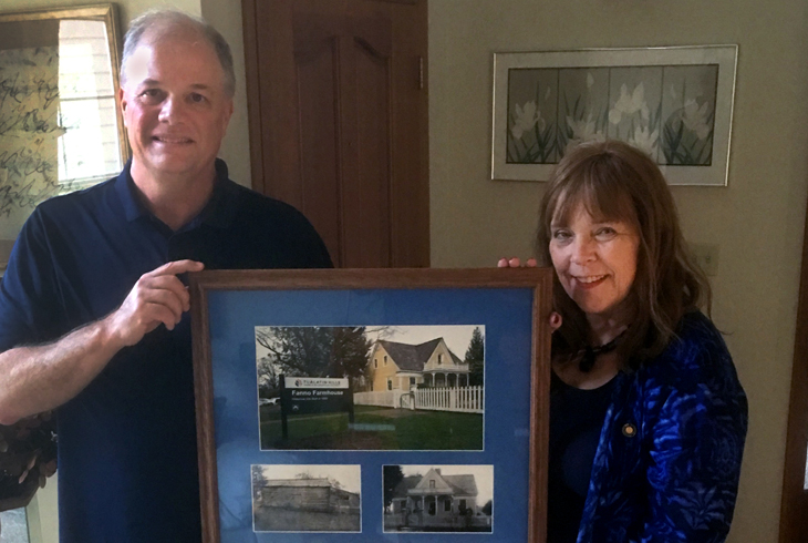John Griffiths presents a photo montage of Washington County's first registered home - Fanno Farmhouse - to Oregon State Rep. Sheri Malstrom.