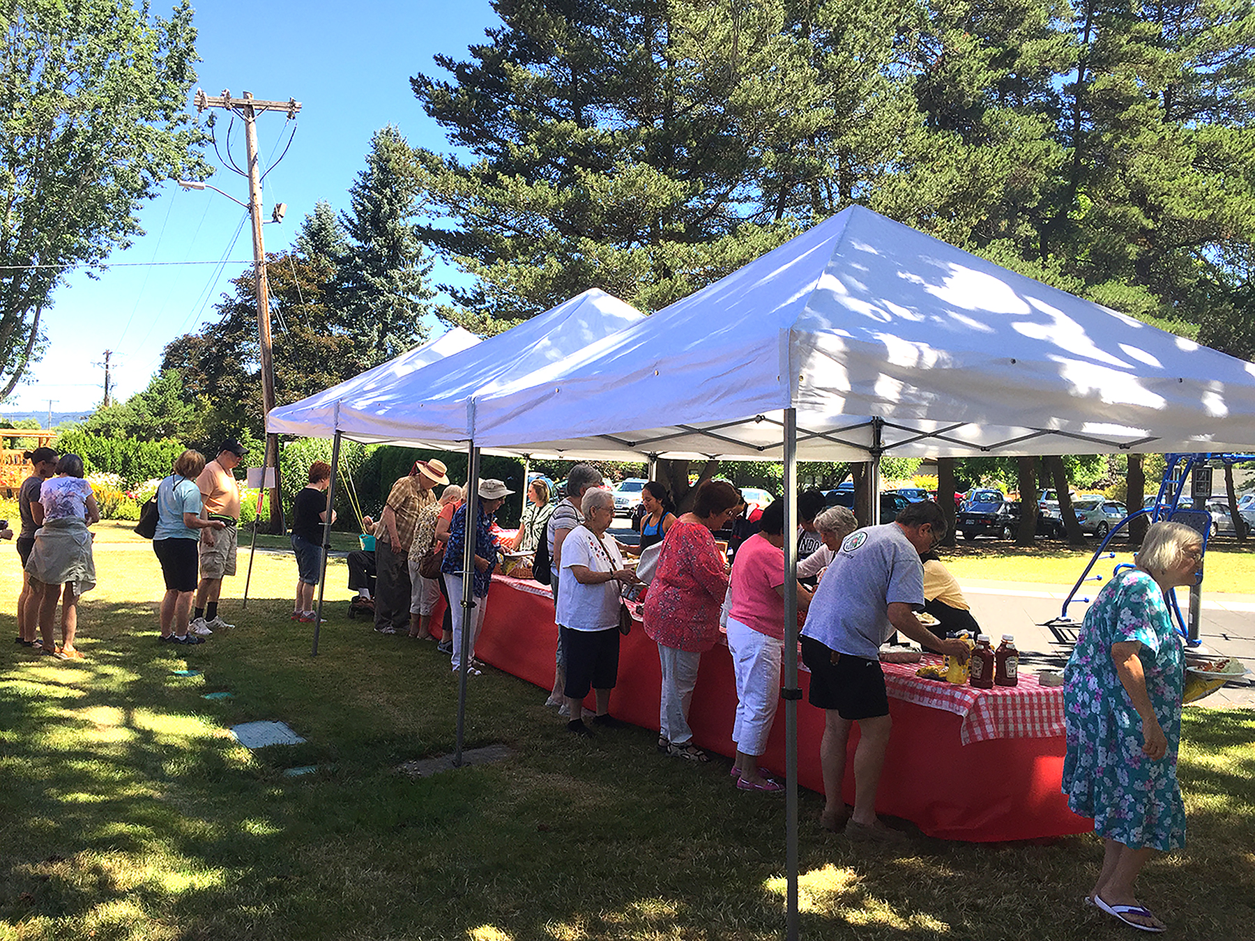 On the back patio at the Elsie Stuhr Center (near downtown Beaverton), hungry patrons line up to load up their plates during the 2017 barbecue.  This year’s event happens on  July 6 from 11:30 am to 1:30 pm.